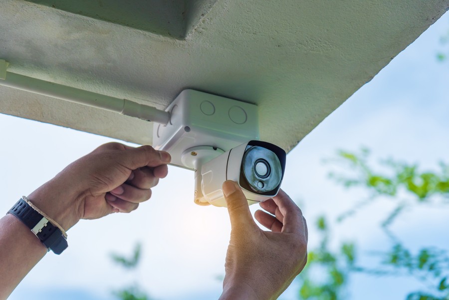a hand wearing a watch installing a security camera for home