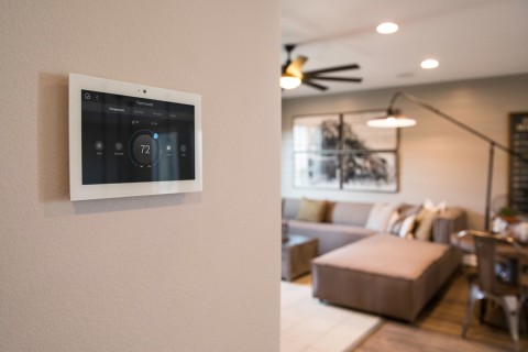 wall-mounted Control4 touchscreen and living in room with couches in the background
