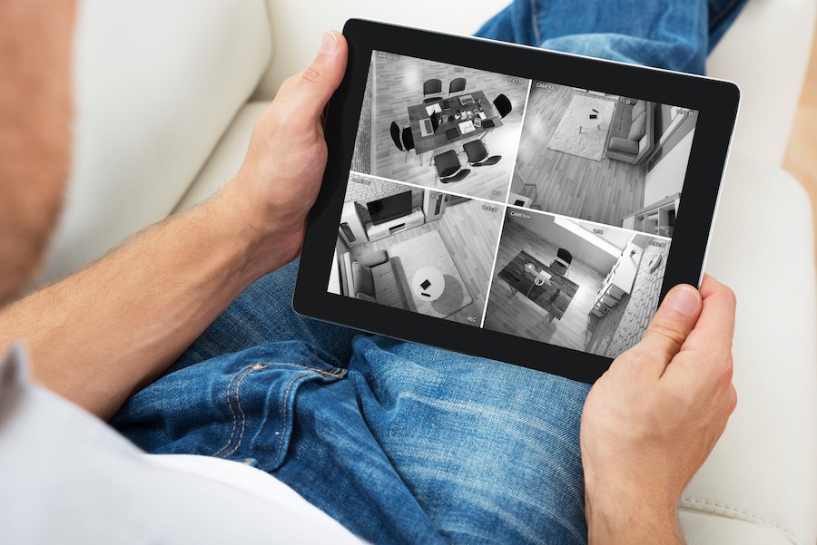 Individual monitoring home security cameras using a tablet.