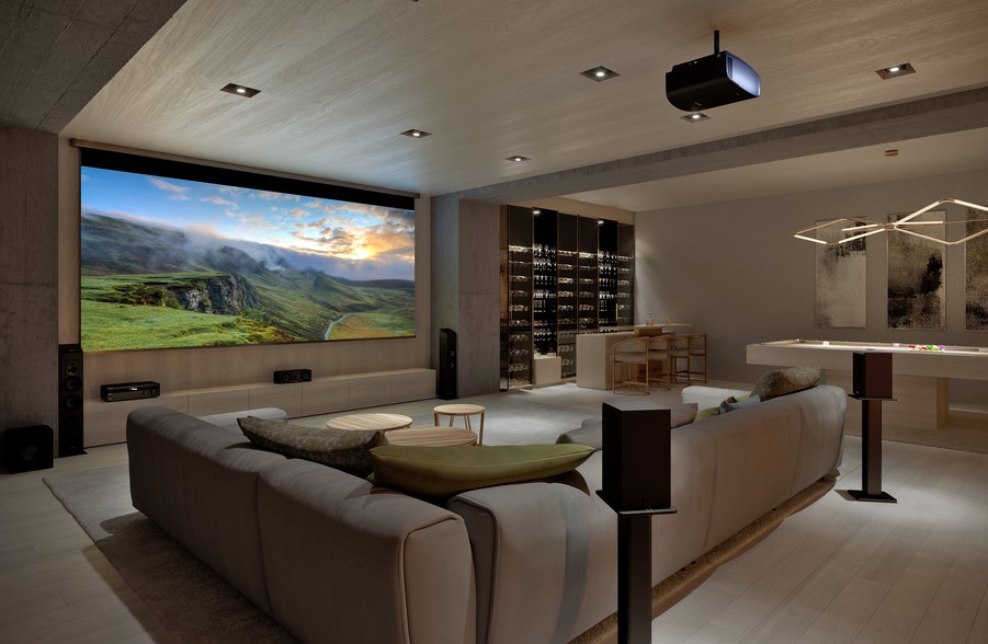 A casual home theater with a large screen, pool table, and surround sound speaker set up.