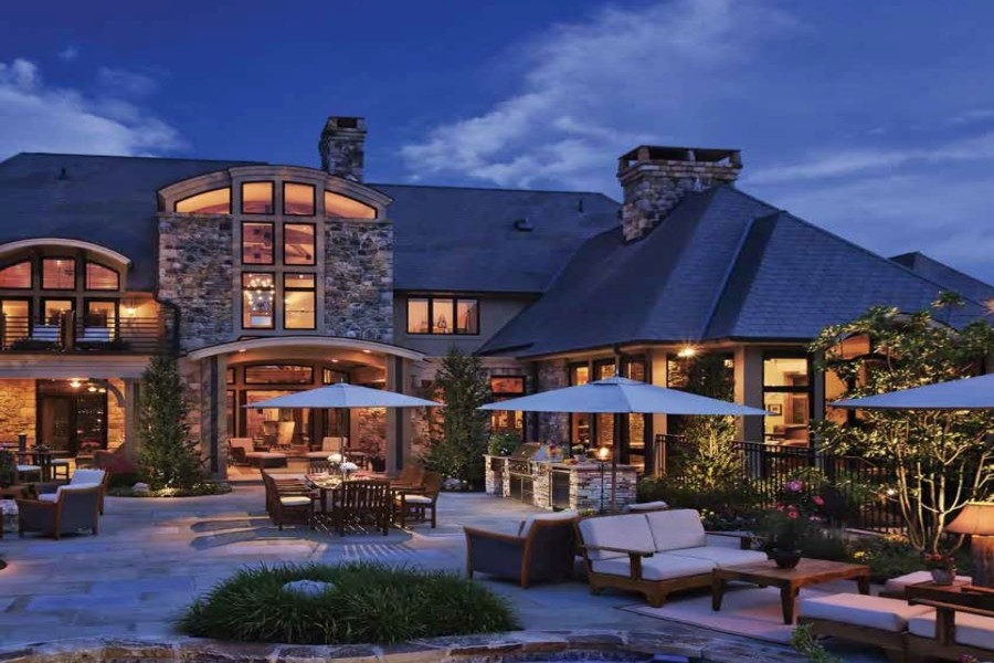A well-lit home with numerous outdoor seating areas and various light fixtures.