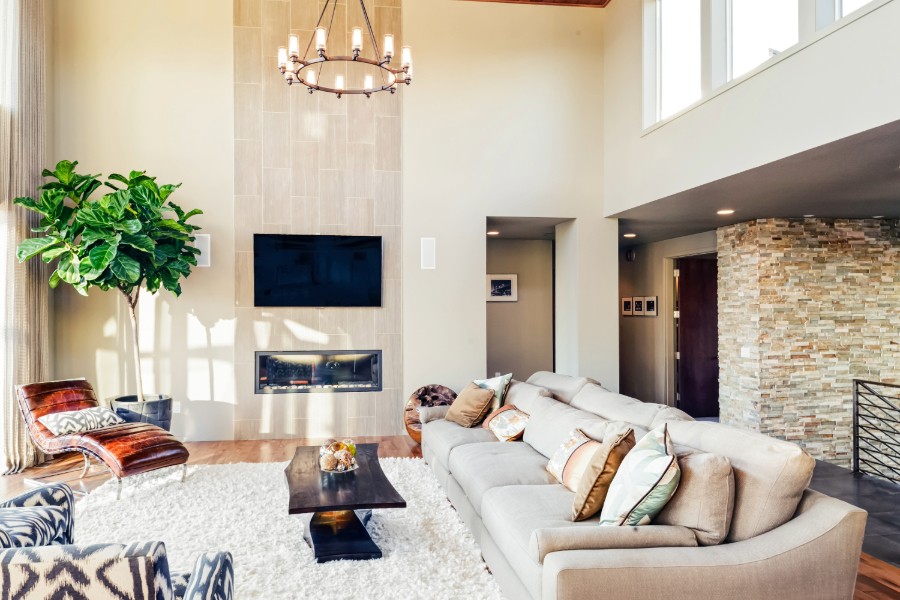 A modern living room with a sofa, a wall-mounted TV, and a fireplace.